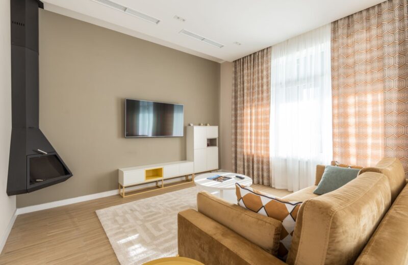 A living room with a beige sofa facing a wall-mounted TV