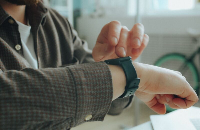 A person checking a smartwatch with a dark strap on their wrist