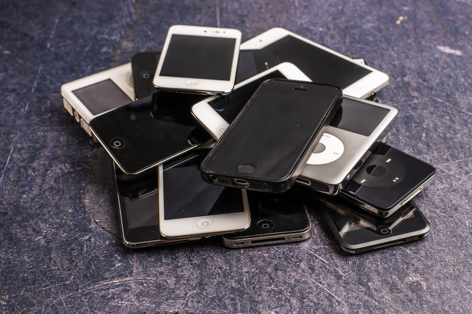 A pile of old phones and music players on a grey cloth, ready to be traded in