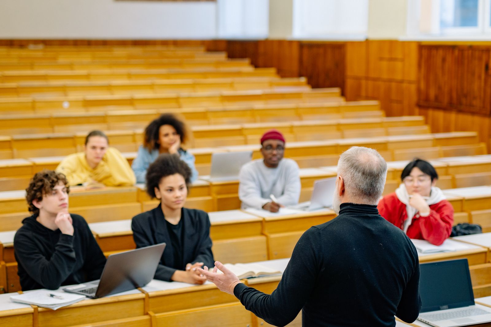 A lecturer talking with students in a tiered lecture theatre