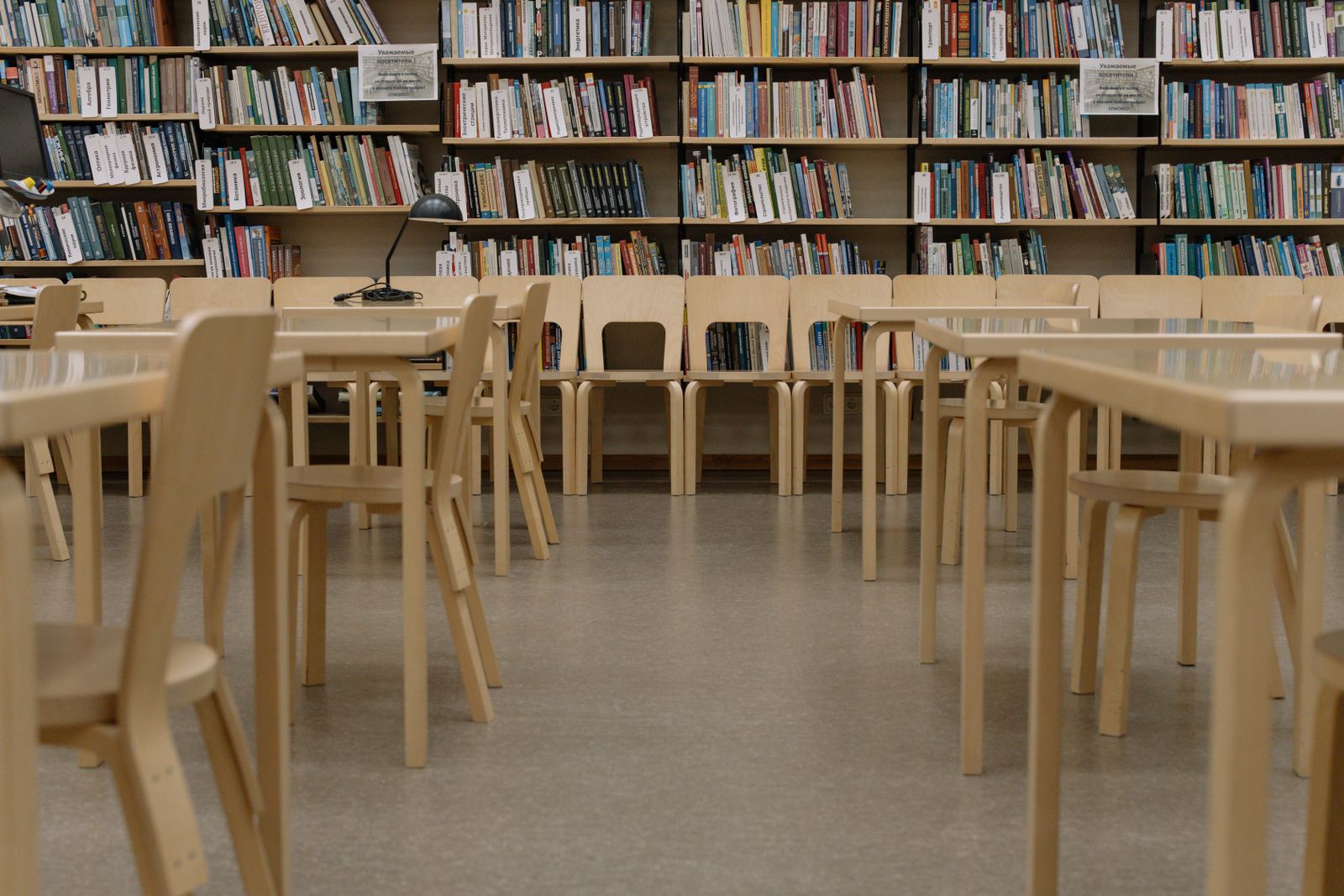 Library reading room with wooden tables and full bookshelves