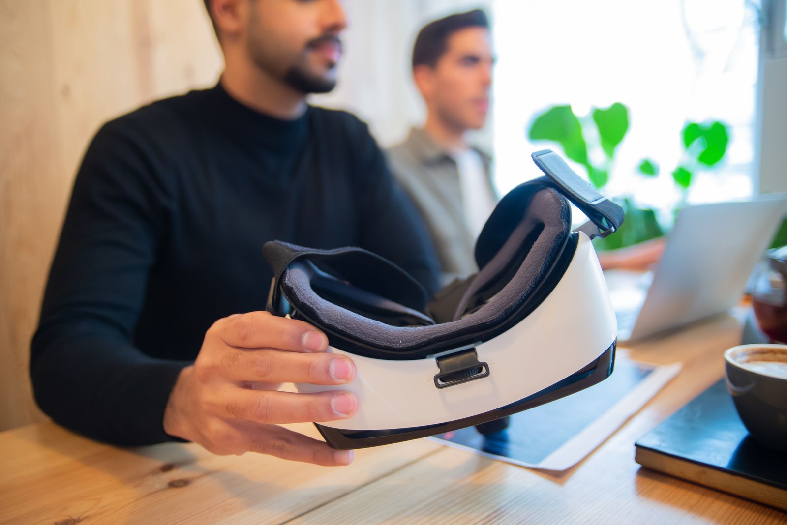 A hand holding a white VR headset with its foam face cover facing up