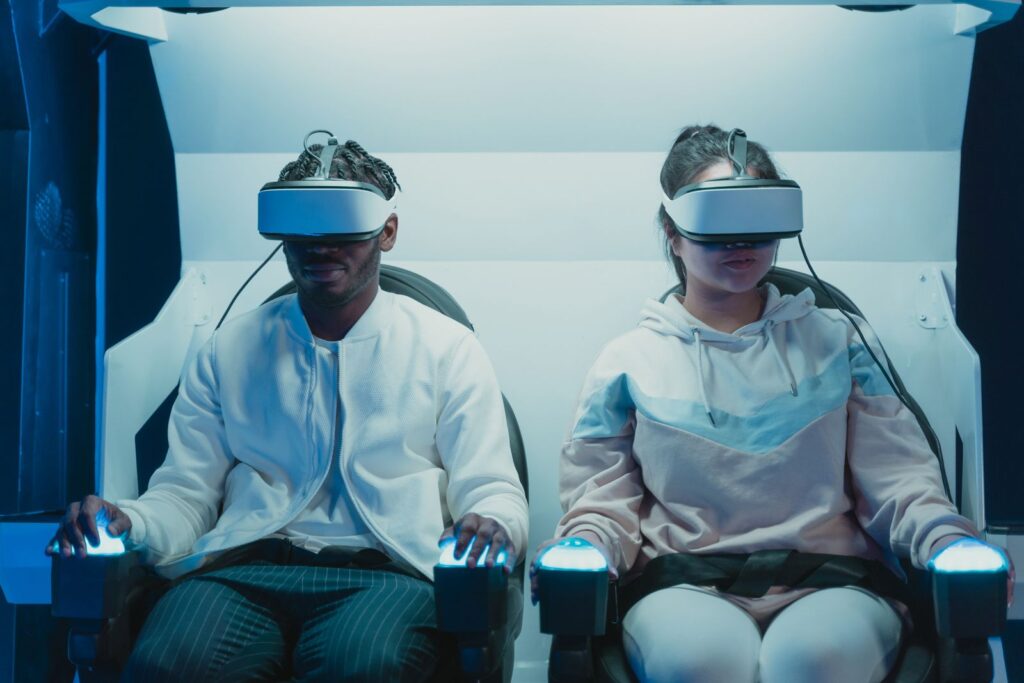 Two players in VR headsets in white seats in a VR arcade