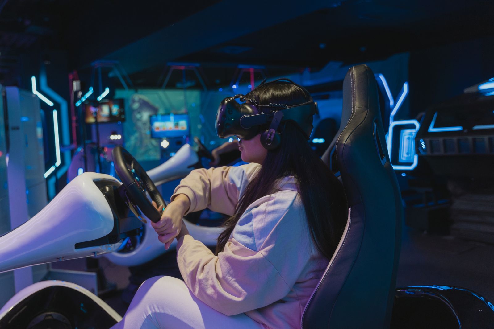 A player in a VR headset holding the wheel of a racing seat