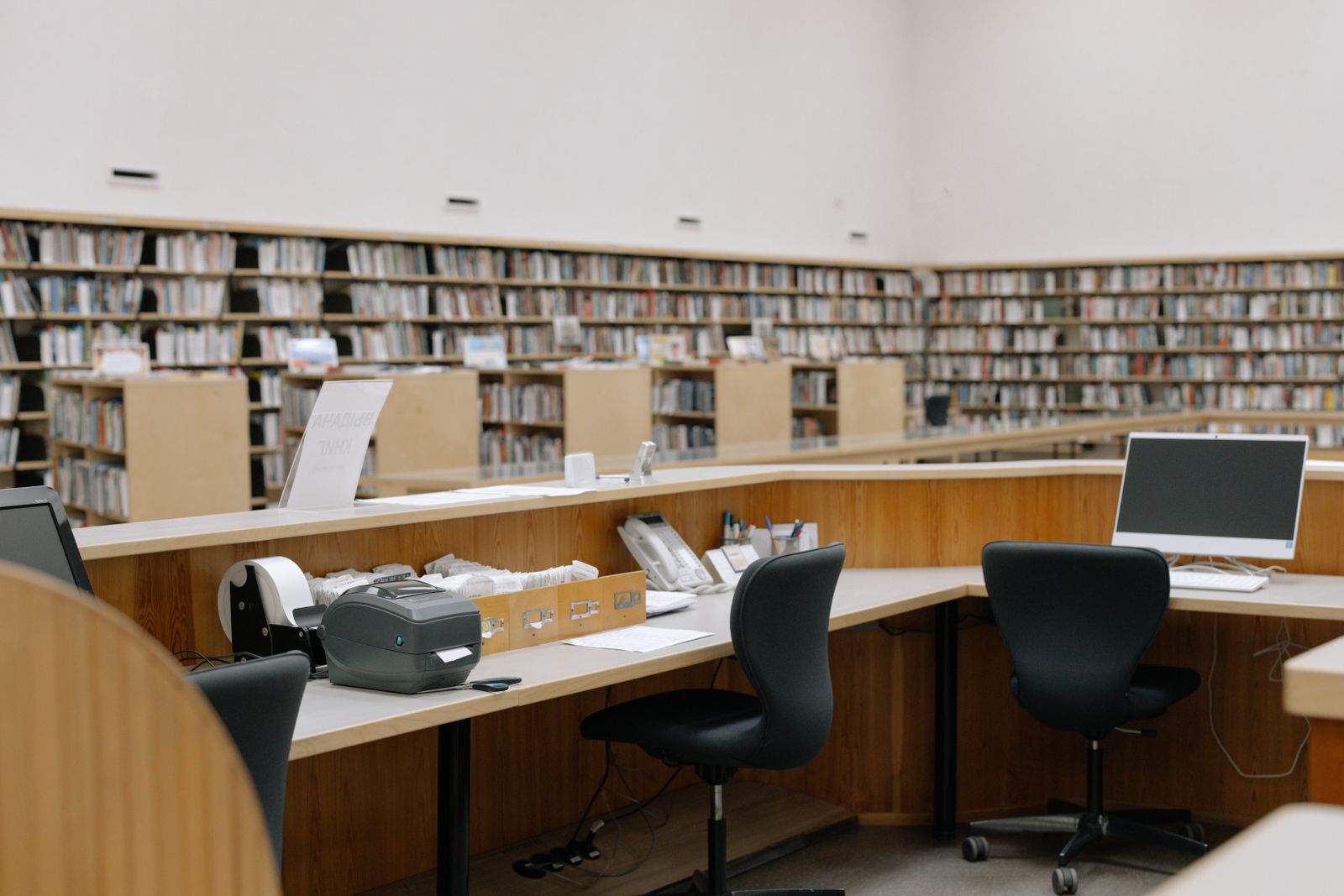 Library help desk with computers in front of tall bookshelves