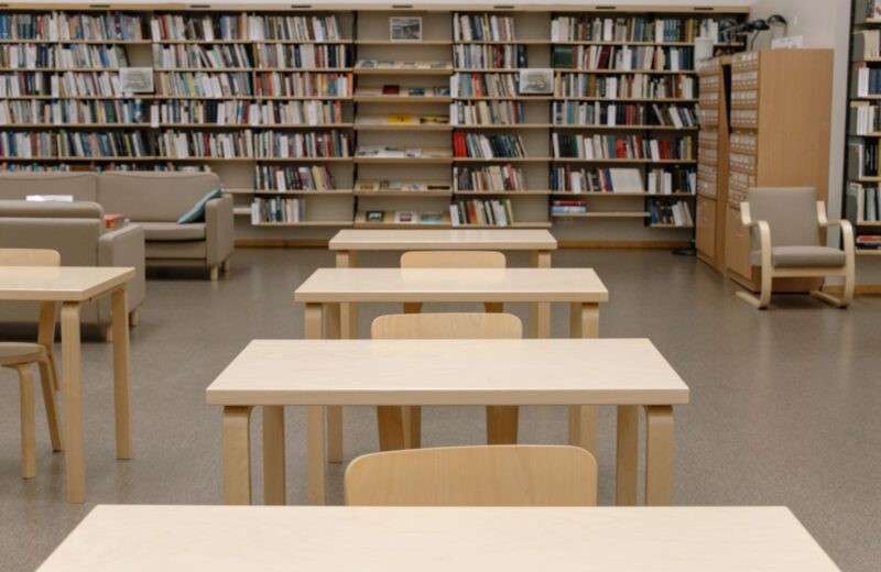 Empty library reading room with wooden tables and full shelves