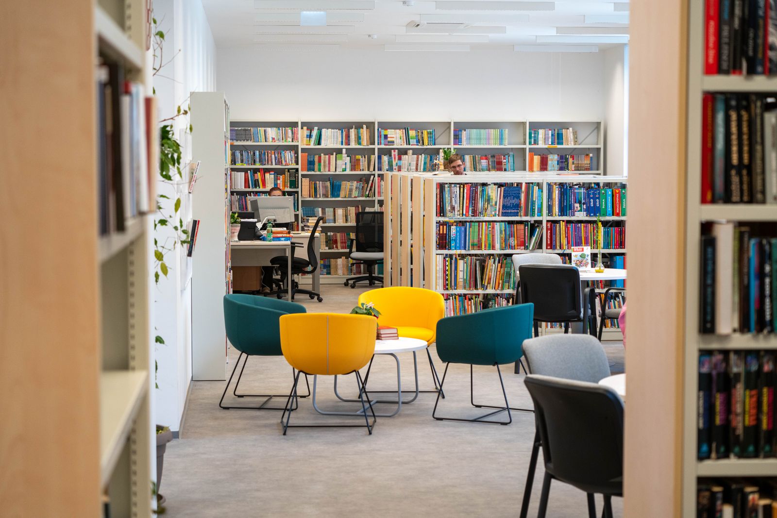 Bright library reading area with bookshelves and coloured chairs