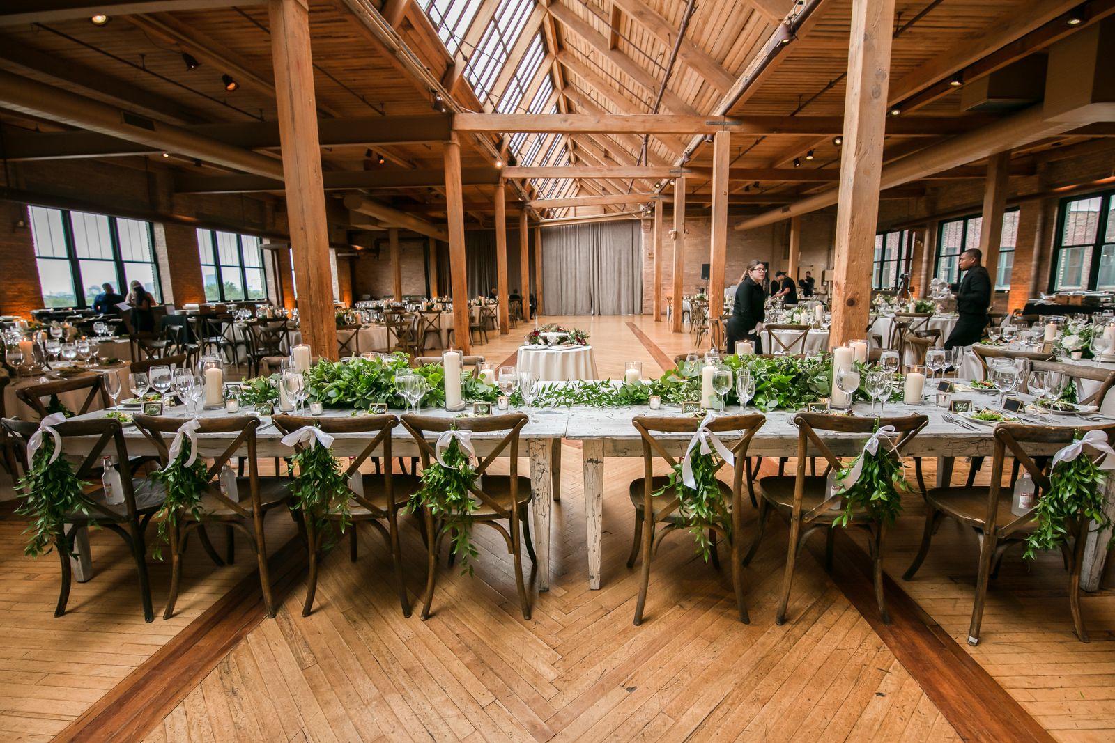 Long tables with green garlands in a brick-walled city venue
