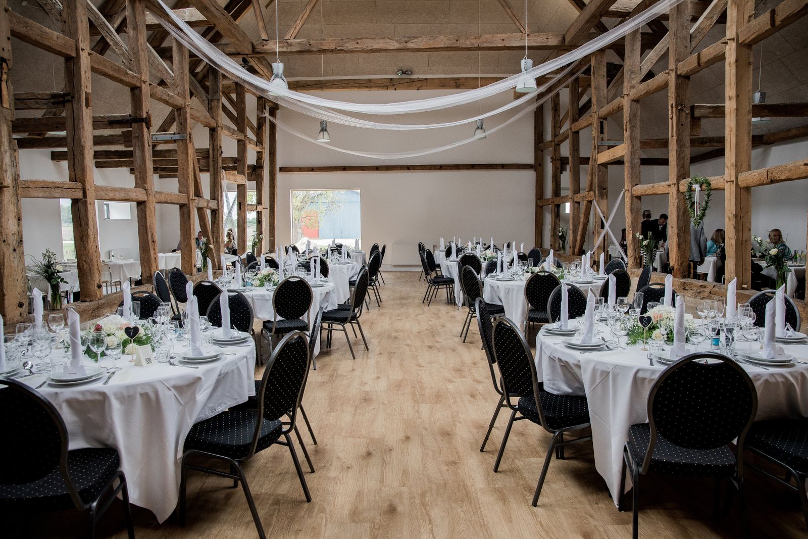 Round tables set for a reception in a rustic farm barn