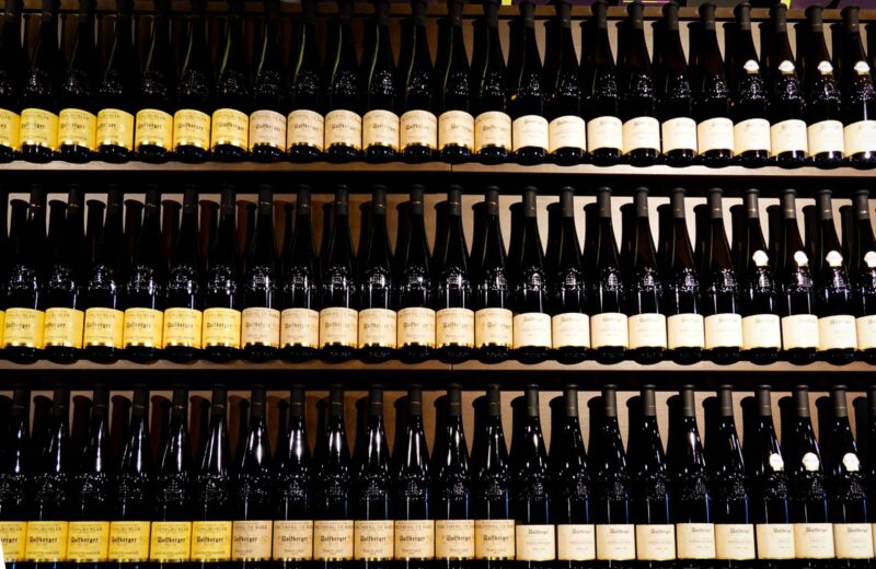 Rows of wine bottles standing on shop shelves