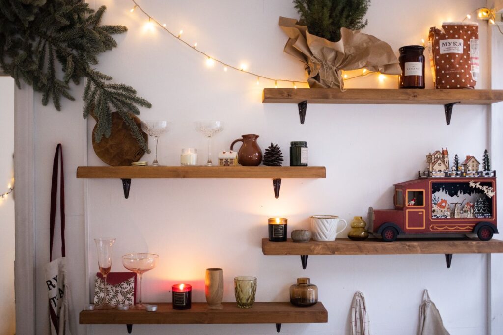 Wooden wall shelves with small Christmas gifts, candles and a toy truck