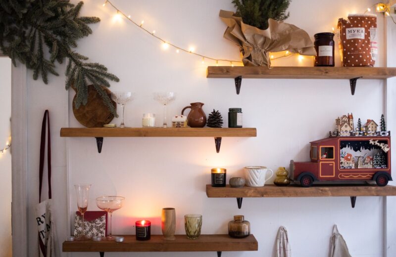 Wooden wall shelves with small Christmas gifts, candles and a toy truck